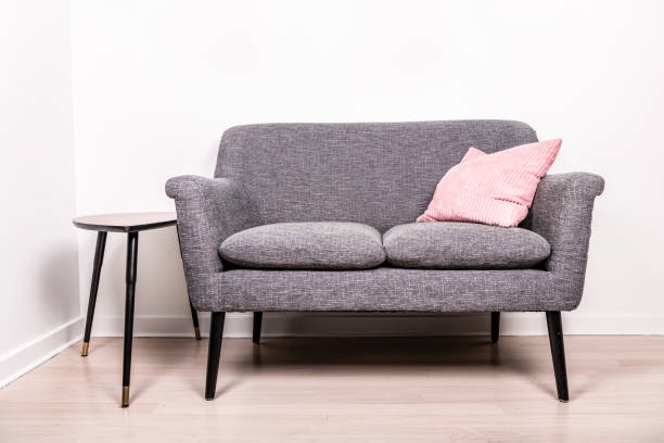 Sillón love seat; un sillón de color gris con un cojín rosa 