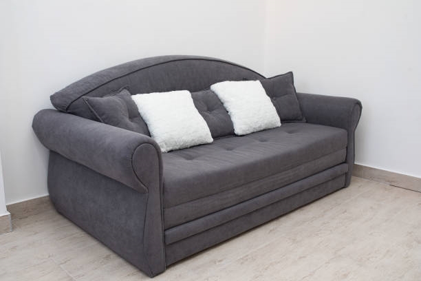 Sillones esquineros; sofá de color gris con cojines blancos  